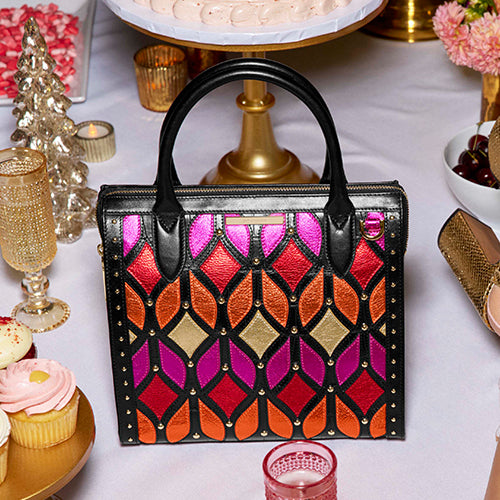 Brahmin Premier collection tote in a geometric multicolor pattern with orange, magenta, and black accents, featuring a boxy silhouette, double handles, and gold hardware.