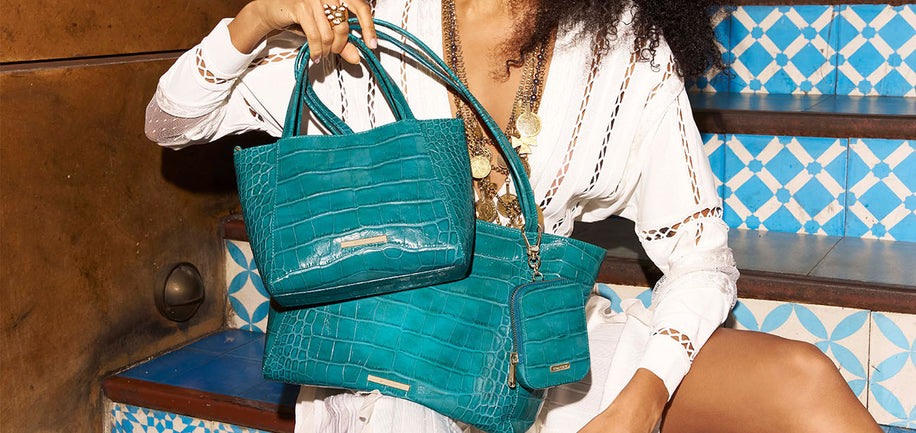 Woman holding a teal handbag with a patterned blue and white background
