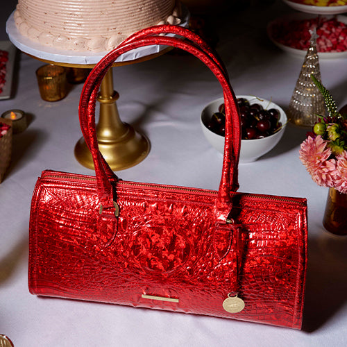Brahmin Melbourne Sophia satchel in glossy red croc-embossed leather with a structured rectangular shape, double top handles, and signature hanging medallion charm.