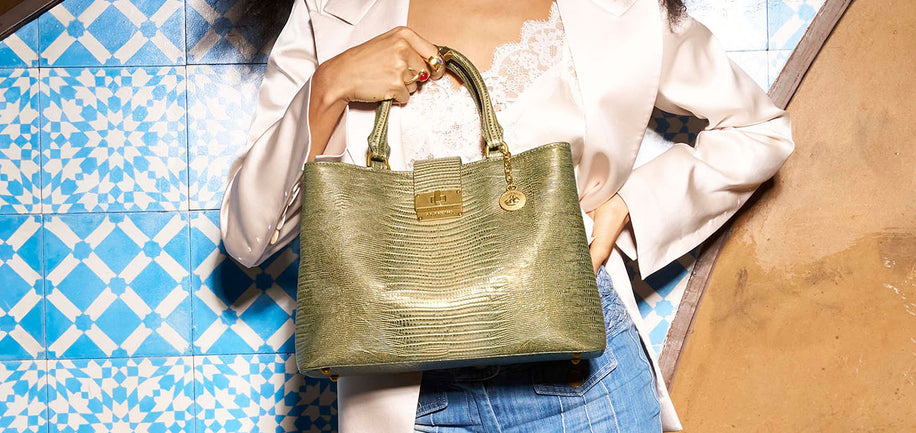 Person holding a green handbag against a blue and white patterned wall.