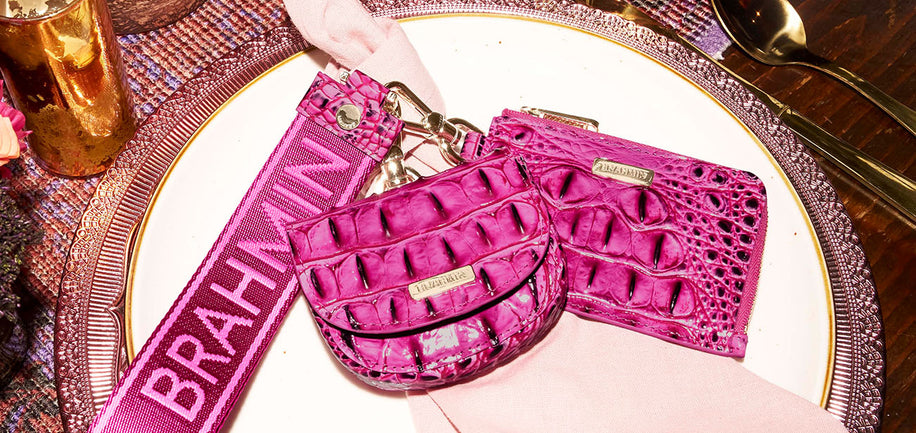 Pink Brahmin wristlet and wallet on a decorative plate with gold accents