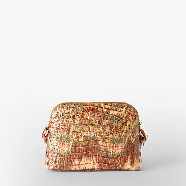 A small dome-shaped crossbody bag with a textured crocodile skin pattern in shades of brown, beige, and muted green, featuring a gold Brahmin plaque on the front. Amal Back View.