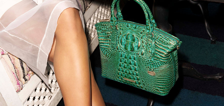 Green textured handbag held by a person with a blurred background