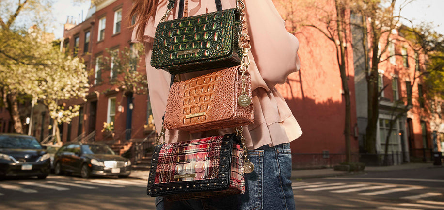Person holding multiple Minuette handbags on a city street