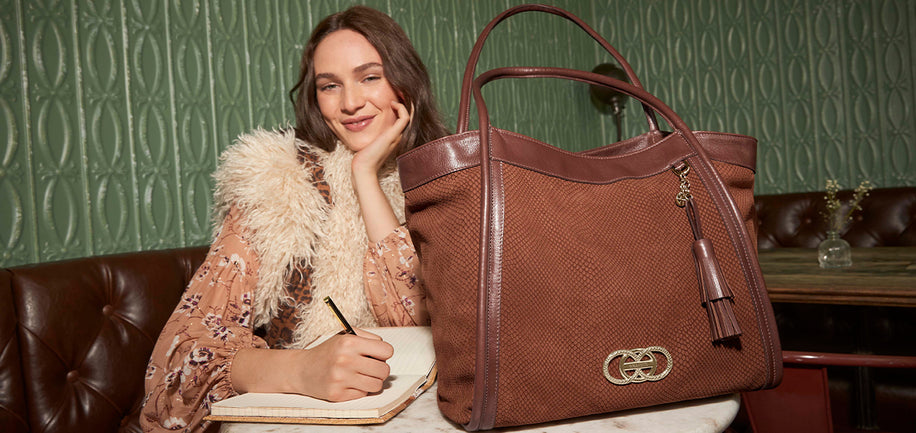 Woman sitting with Sparkling Cider Deveron Bailee on a table against a green, patterned wall.