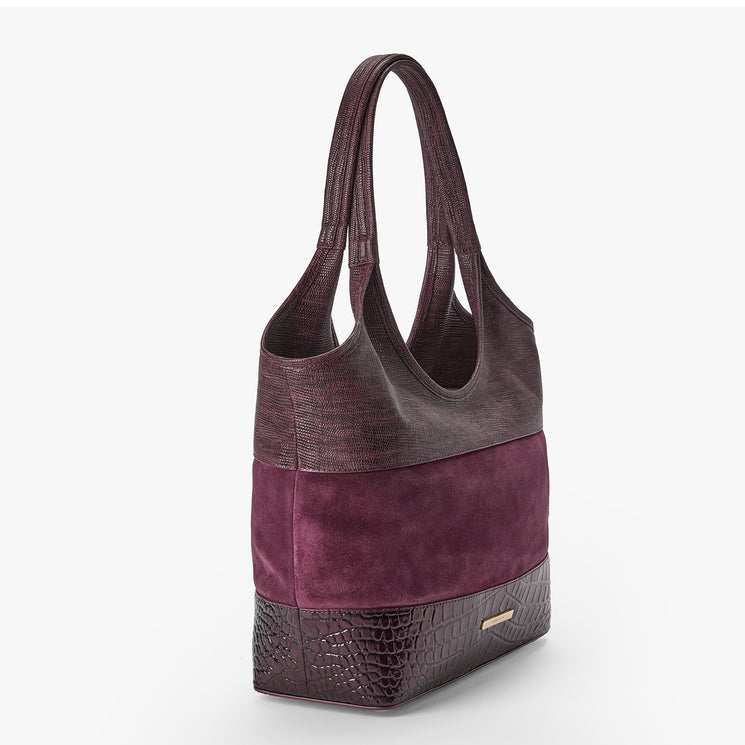 A structured shoulder bag with a color-blocked design featuring textured dark plum leather, a central deep purple suede panel, and a bottom textured dark plum leather base, shown on a light gray background.