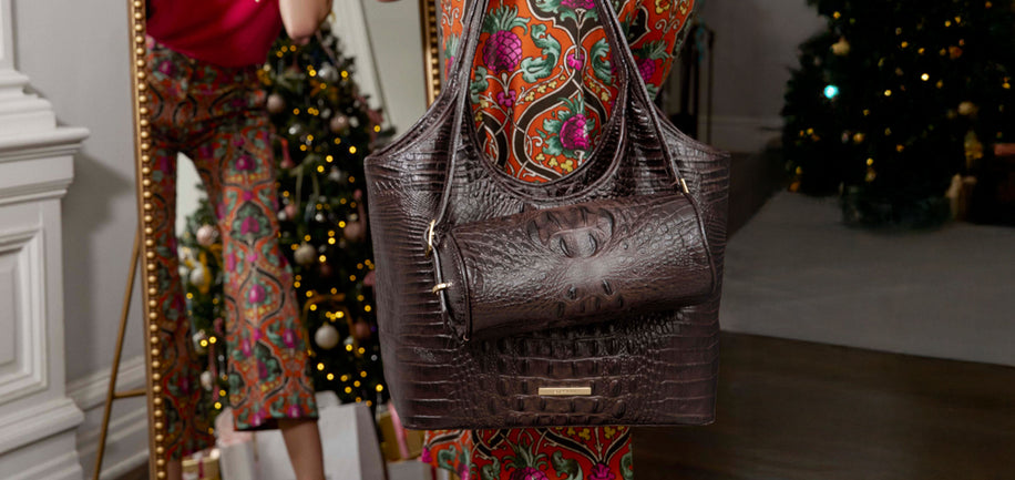 Brown handbag held by model with a decorated Christmas tree in the background