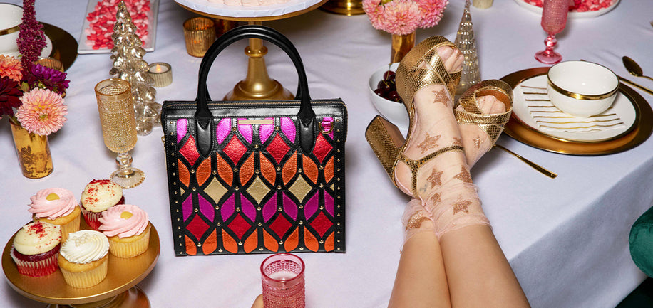 Colorful handbag on a table with cupcakes and decorative items