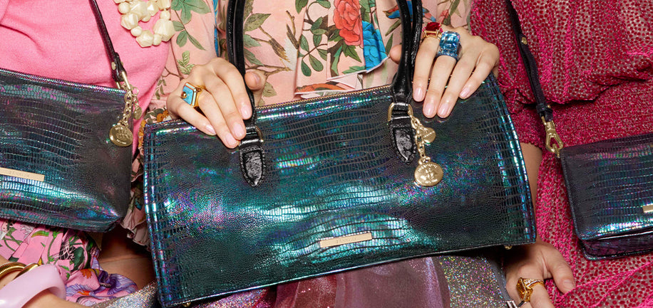 Close-up of a model holding a multi colored metallic Sophia satchel