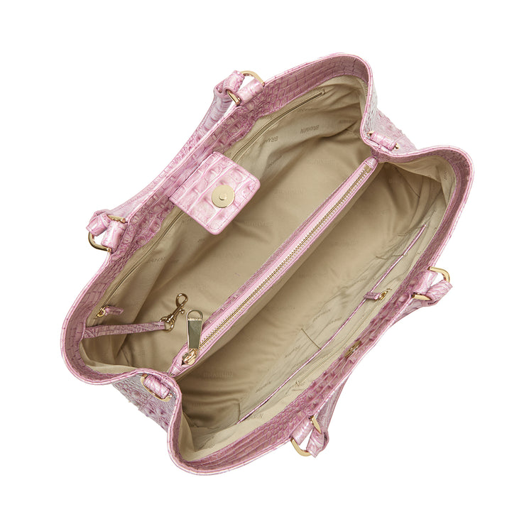 Top view of an open Brahmin pink textured handbag with a structured silhouette, beige interior, gold hardware, zippered center pocket, side compartments, snap closure flap; designed for hand or arm carry.