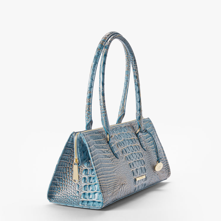 A structured blue crocodile-embossed handbag with dual top handles, gold-tone hardware, and a small round metal charm, photographed on a clean white background.