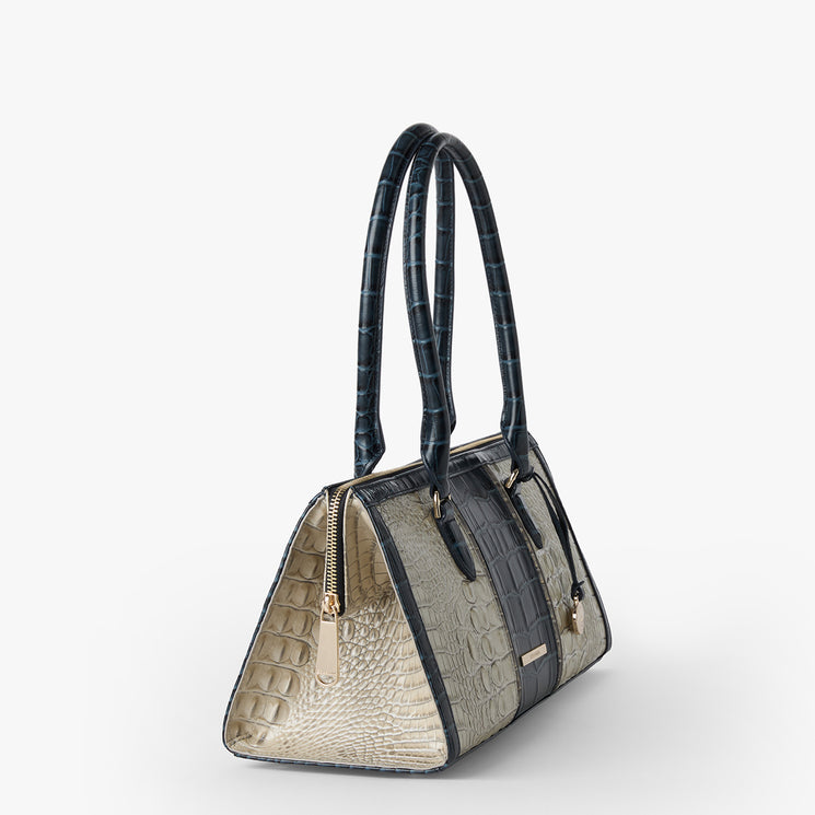 Brahmin structured handbag in cream and navy with embossed, animal-inspired pattern, gold-tone zipper hardware, dual long shoulder straps, and a classic silhouette on white background.