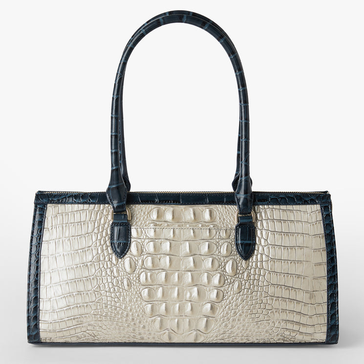 Brahmin Satchel with cream textured center panel, dark blue textured edges and rolled handles, featuring a rectangular silhouette and gold hardware, shown on a white background.