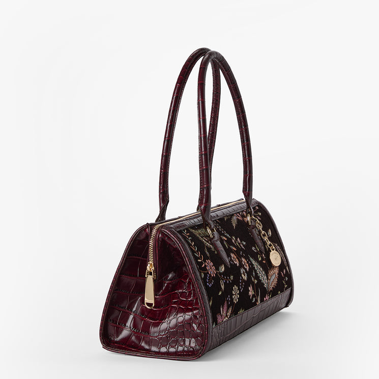 A structured handbag with a glossy dark burgundy crocodile-embossed finish on the back and sides, combined with a floral pattern on the front panel. It features dual top handles, a gold-tone zipper, and a hanging gold charm on a clean white background.