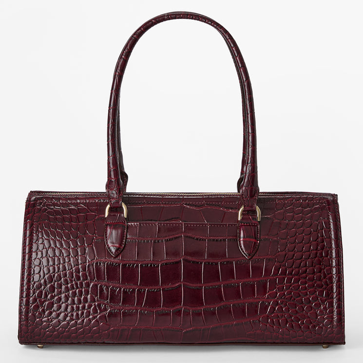 A structured handbag with a glossy crocodile-embossed texture in deep burgundy, featuring dual top handles and gold-tone hardware, set against a plain light gray background.