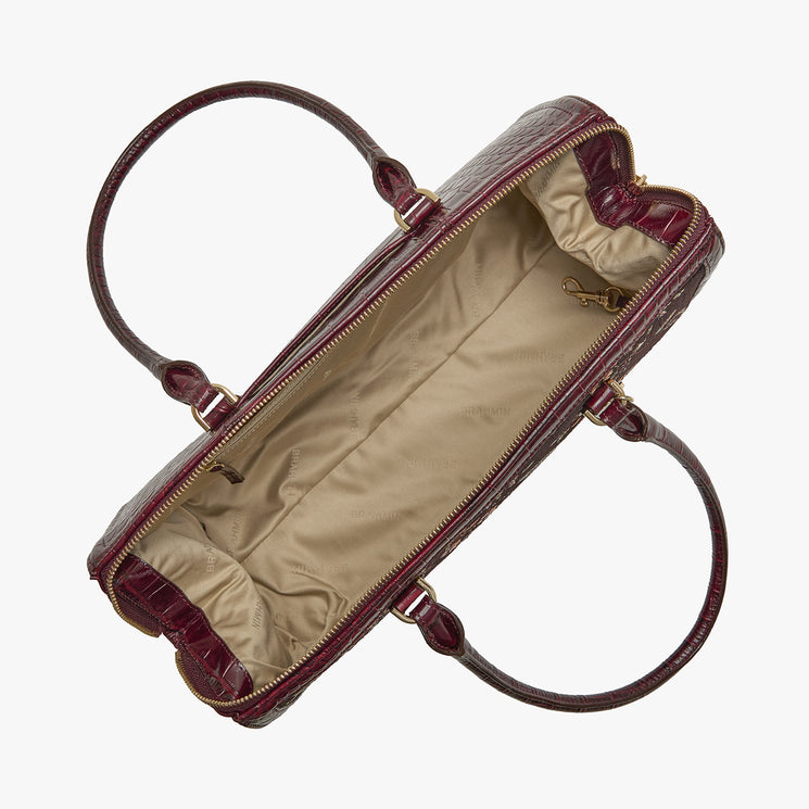 A top-down view of a dark burgundy crocodile-embossed leather handbag with a beige interior, shown open on a light gray background.