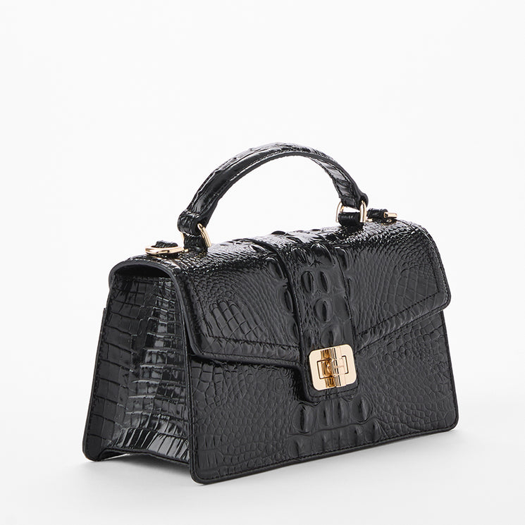 A structured black crocodile-embossed handbag with a top handle and gold-tone hardware, photographed on a clean white background. Side view.