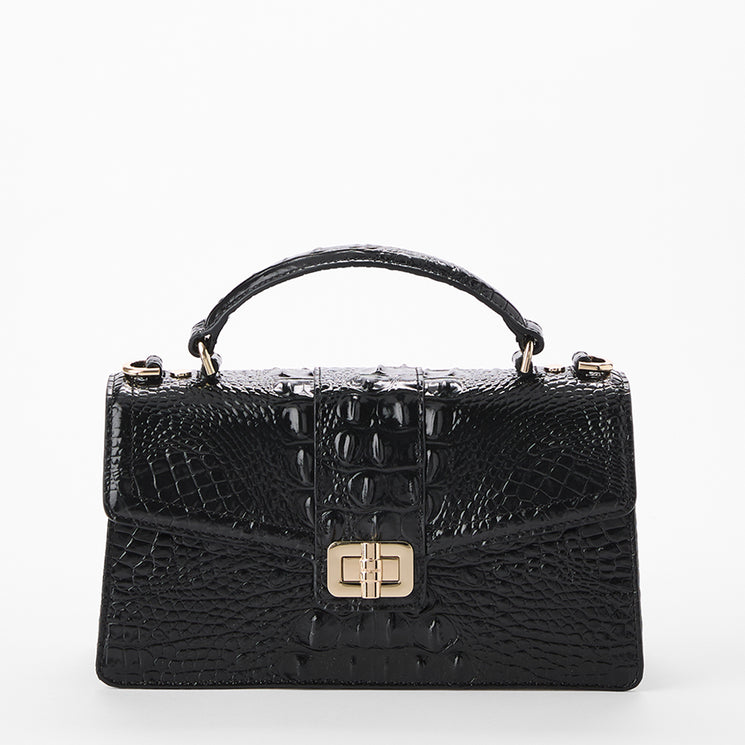 A structured black crocodile-embossed handbag with a top handle and a gold-tone turn-lock clasp, shown against a plain white background. Front view with no strap.