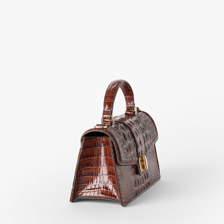 A small brown crocodile-embossed handbag with a top handle and gold-tone hardware, photographed on a clean white background. Side view.
