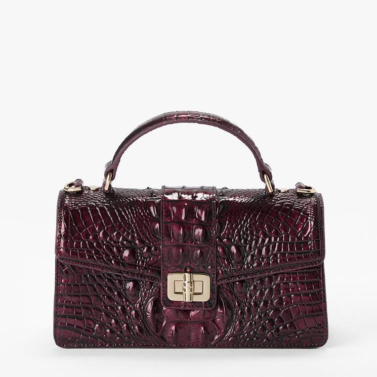 A structured top-handle handbag in glossy embossed crocodile leather, shown on a clean white background. The handbag is a deep burgundy/plum color with a prominent gold-tone turn-lock clasp on the front flap.