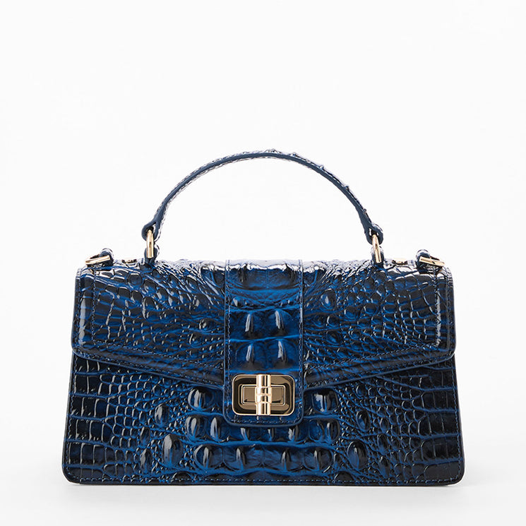 A structured blue crocodile-embossed handbag with a top handle, gold-tone hardware, and a front turn-lock closure, photographed on a clean white background. Front view.