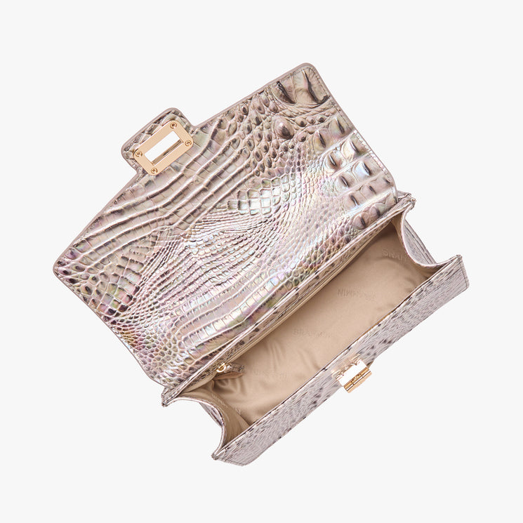 Brahmin metallic embossed handbag with gold clasp, beige lining, and small interior zip pocket, shown open from above on a white background. Features textured pattern and structured silhouette.