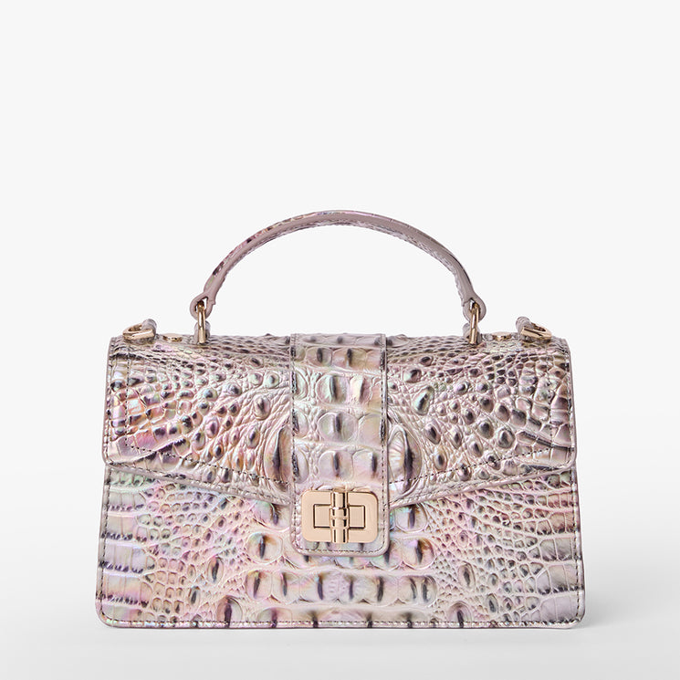 Brahmin iridescent handbag with embossed texture, top handle, structured silhouette, front flap, gold turn-lock closure, and subtle pattern detailing. Shown against a white background.