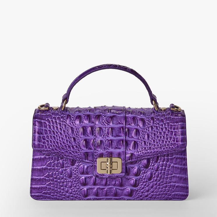 Brahmin purple embossed leather satchel with structured silhouette, single top handle, gold-tone clasp closure, and textured pattern, shown on a plain white background. No strap or interior details visible.