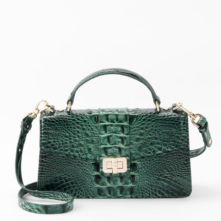 Brahmin Genie satchel in dark green with a textured, embossed pattern. Features a top handle, detachable shoulder strap, and gold-tone turn-lock closure.