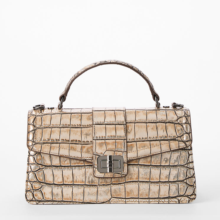 A structured top-handle handbag with a crocodile-embossed texture in a distressed beige and brown colorway, featuring a silver-tone turn-lock closure on the front flap. Front view.