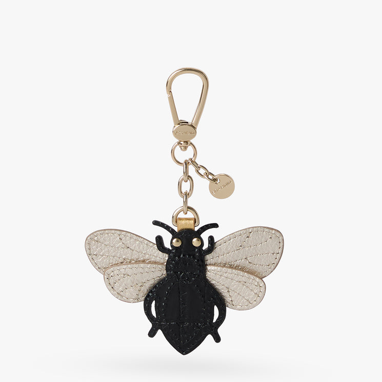 A bee-shaped keychain charm featuring a black textured body, clear patterned wings, and gold-tone hardware including a lobster clasp and small round tag, shown on a light gray background.