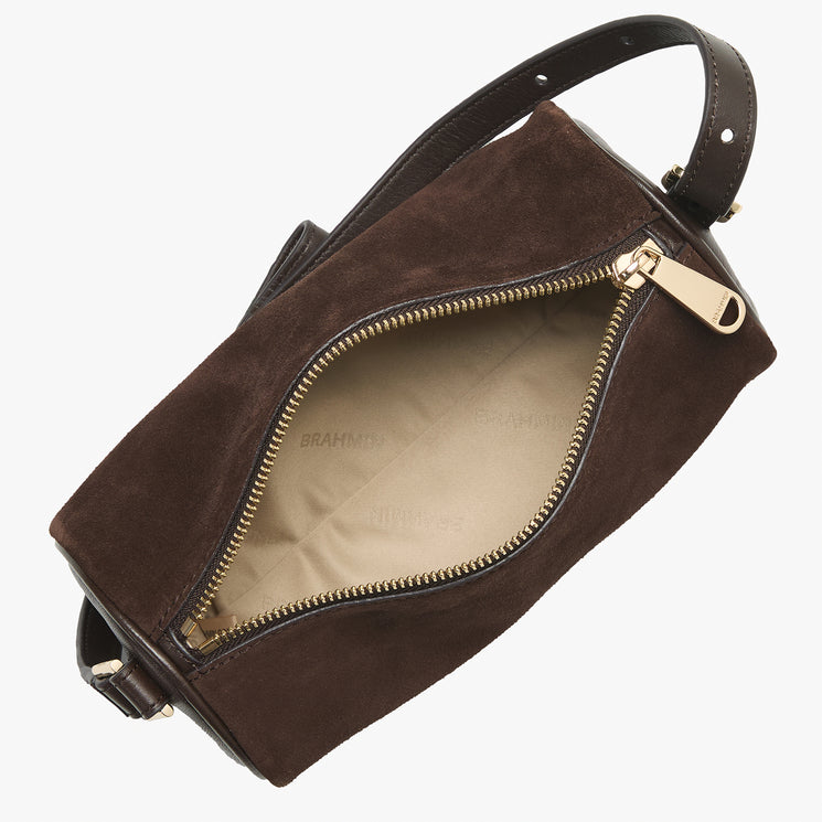A dark brown suede shoulder bag shown open, displaying its beige interior lining and gold-tone zipper. The brand name 'BRAHMIN' is subtly printed on the lining.