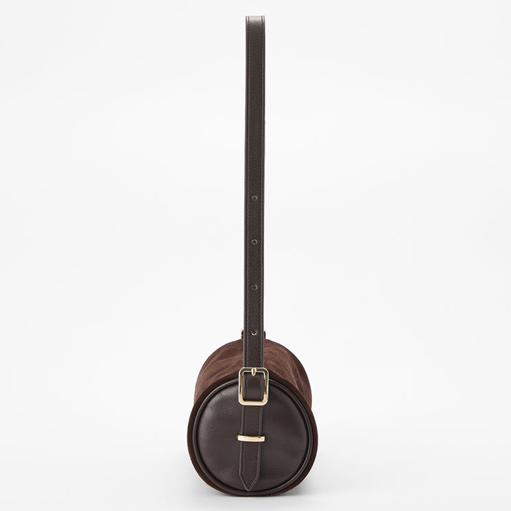 A dark brown leather cylindrical shoulder bag with a matching long strap and a gold-tone buckle, shown against a plain white background.