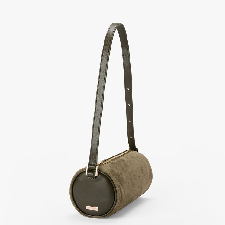 An olive green cylindrical shoulder bag with a dark olive green leather strap and a small gold-tone logo plaque on a light gray background.