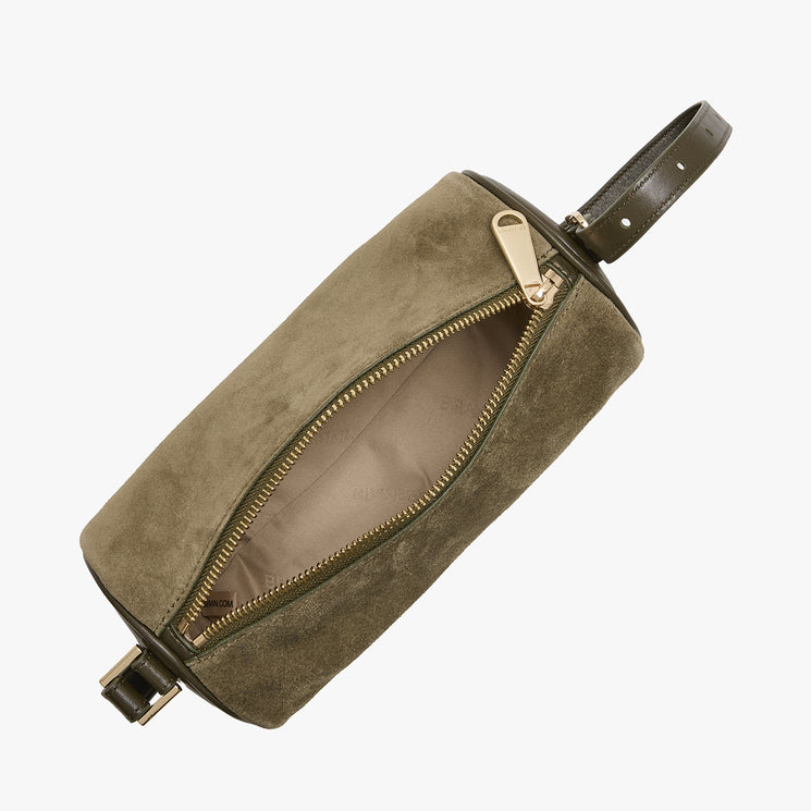 An olive green suede shoulder bag with an open gold zipper, showing a beige interior lining, and a dark green leather strap, photographed on a light gray background.