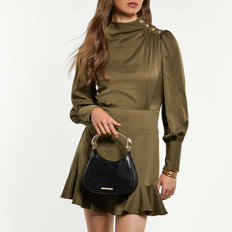 Woman wearing a green dress holding Brielle handbag on a white background