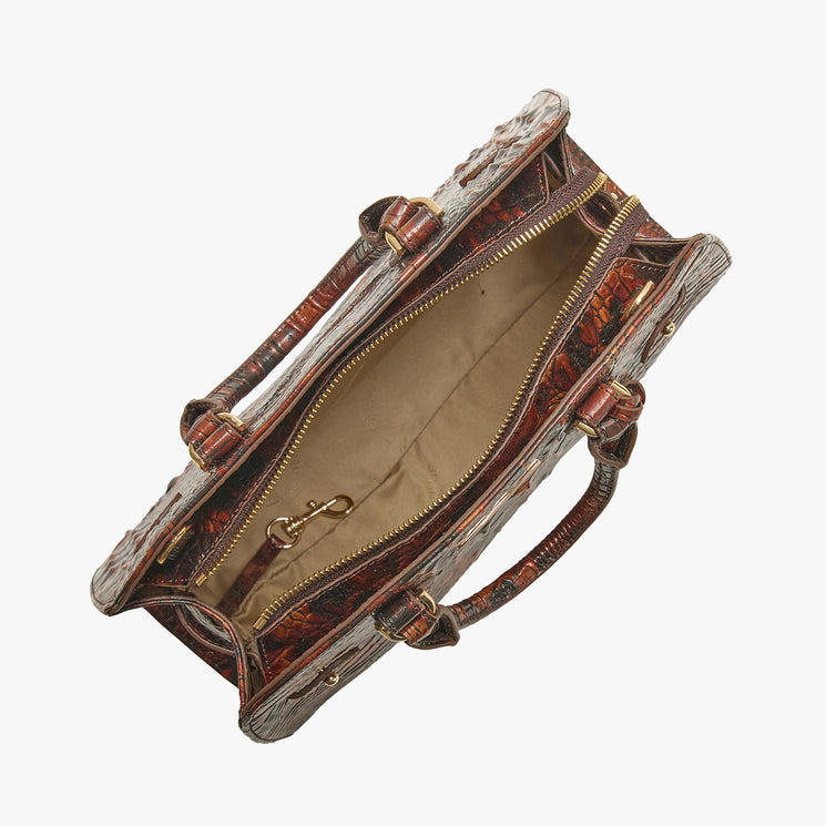 An open brown textured handbag with gold-tone hardware, showing a beige interior lining and handles, photographed on a light gray background.