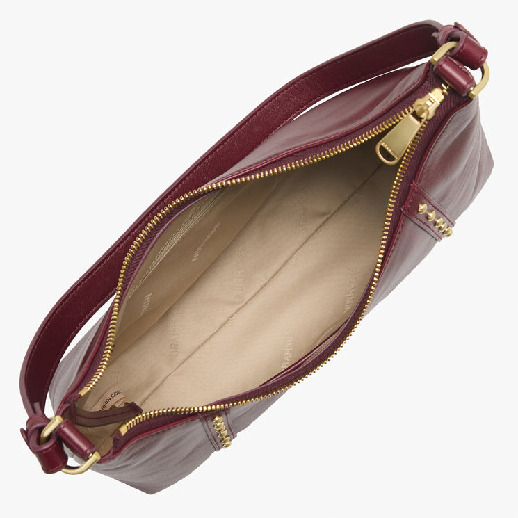 Open top view of a Brahmin burgundy leather purse with gold zipper, beige fabric lining, and adjustable shoulder strap. Interior is empty and clean, showing the bag’s organized silhouette and premium hardware details.