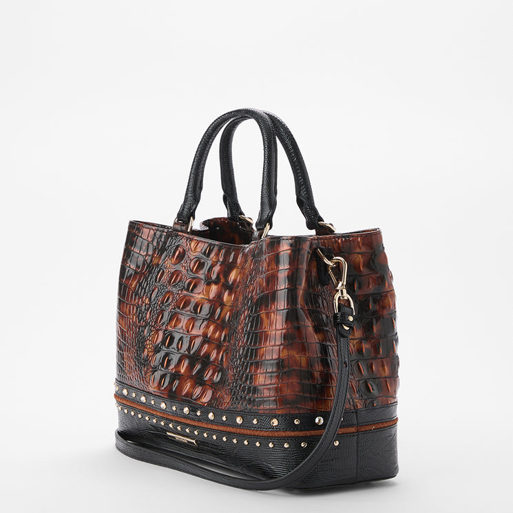 A structured handbag with a brown and black crocodile-embossed pattern, featuring black leather handles, a matching shoulder strap, and a studded base trim, photographed on a light gray background.