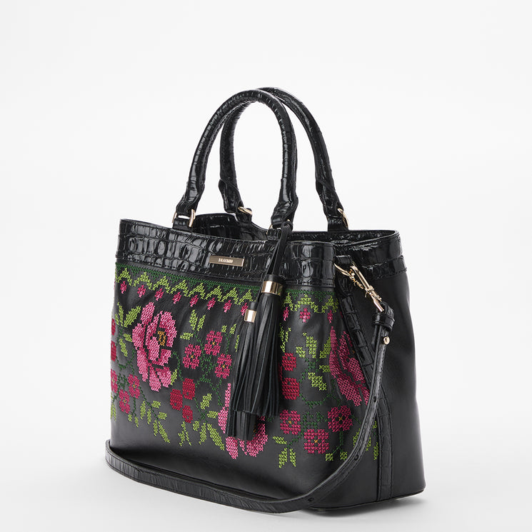 Brahmin black handbag with double top handles, detachable shoulder strap, gold-tone hardware, and a front tassel. Features pink and green floral embroidery. Shown on a plain white background, exterior view only.