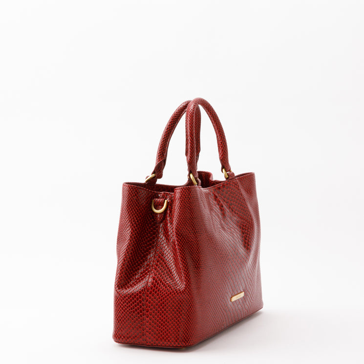 Red BRAHMIN Small Denise satchel featuring a textured, scale-like embossed pattern, gold-tone hardware, two top handles, and an adjustable crossbody strap.