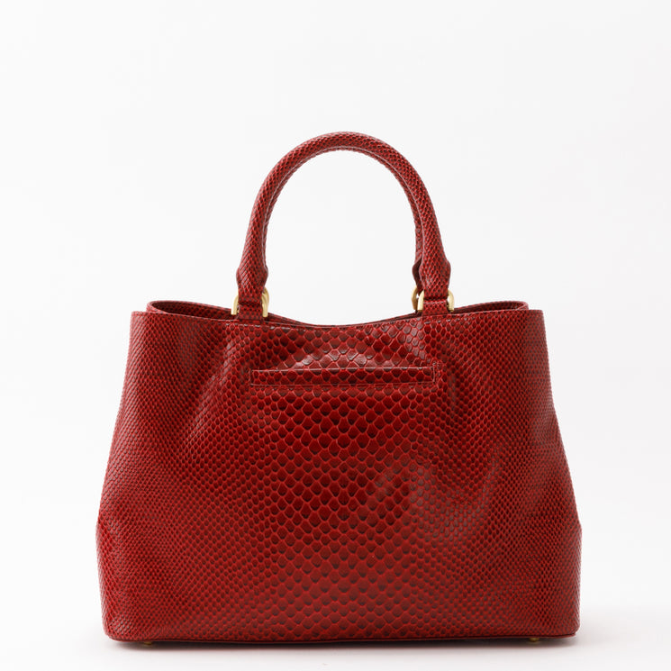 Small red Brahmin Denise satchel featuring a structured silhouette, textured scale-like embossed pattern, gold-tone hardware, two top handles, and an adjustable crossbody strap.