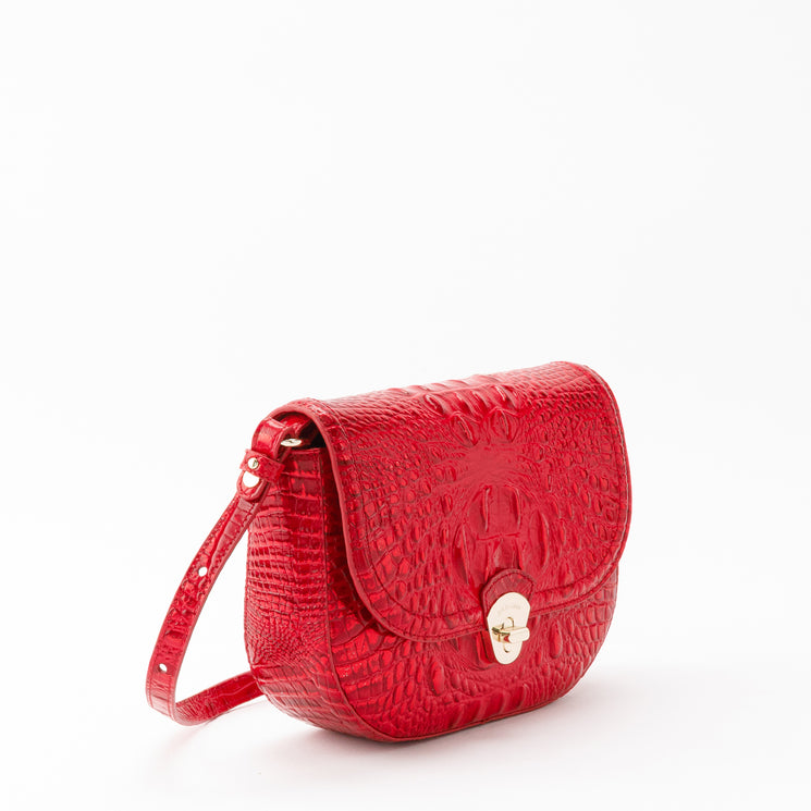 Brahmin Portia crossbody bag in holiday red with a saddle silhouette and textured, croc-embossed finish. Features a fold-over flap, gold-tone turn-lock closure, and an adjustable shoulder strap.