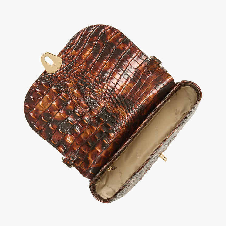 A brown crocodile-embossed leather handbag shown open, displaying its interior lining and gold-tone hardware, set against a plain light gray background.