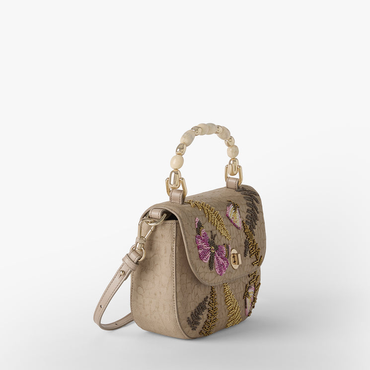 Beige handbag with butterfly and fern designs on a white background. Portia side view.