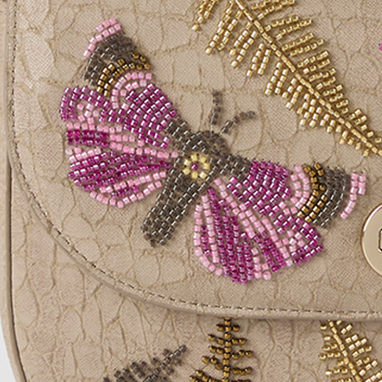Close-up of a beaded butterfly design on a textured surface with gold accents. Portia close up.