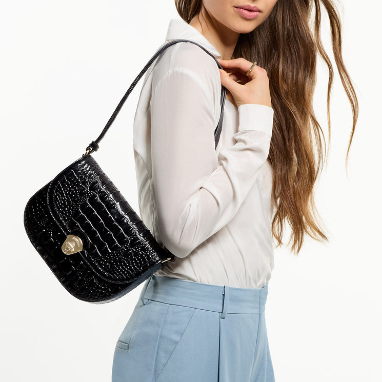 Woman holding Portia in Black Melbourne with a white blouse and light blue pants on a plain background