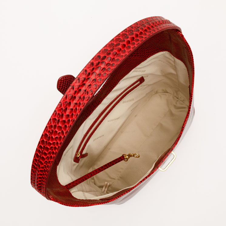 Interior view of a textured red Brahmin Gwynne bag showing a light lining, interior pockets, a zippered compartment, and a gold-tone lobster clasp key clip.