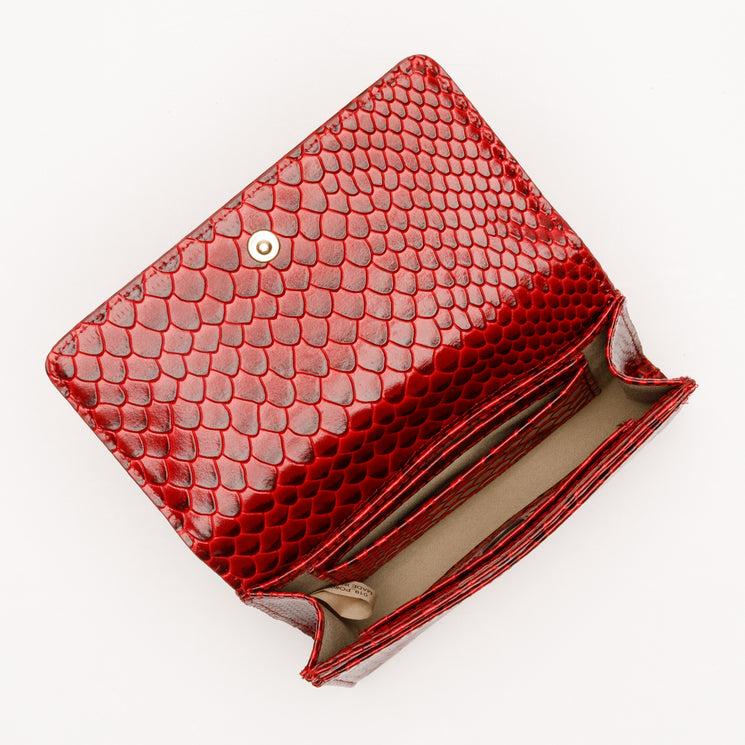 Open red Brahmin Kerra wallet with a snap closure and textured, scale-like pattern, featuring interior credit card pockets and compartments.