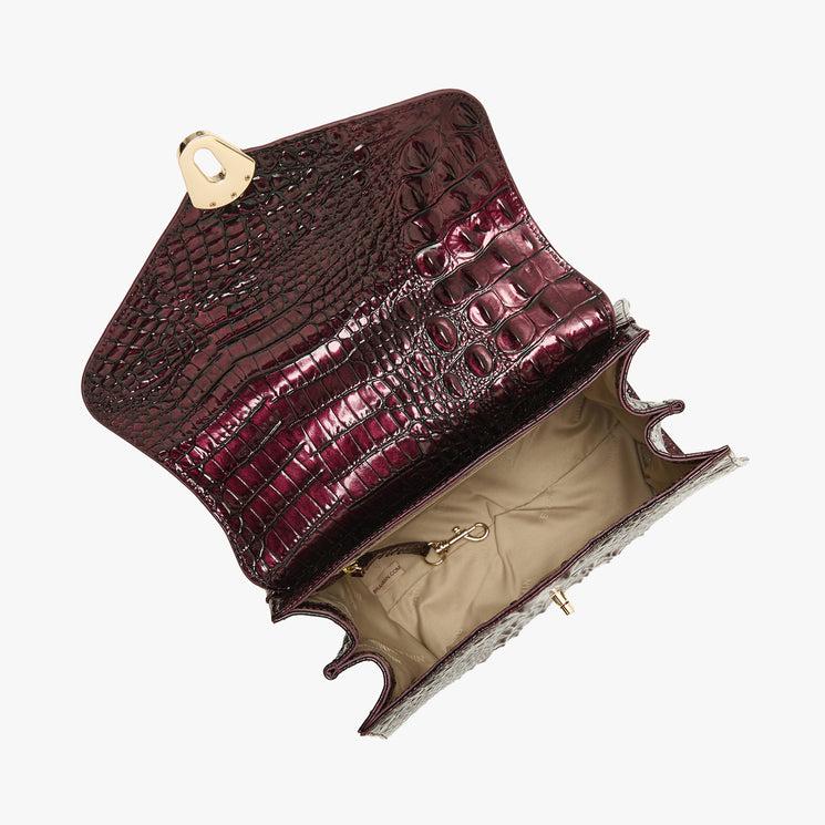 A handbag with a glossy, embossed crocodile pattern in deep burgundy. The bag is shown open, revealing a beige interior lining and gold-tone hardware, set against a plain white background.